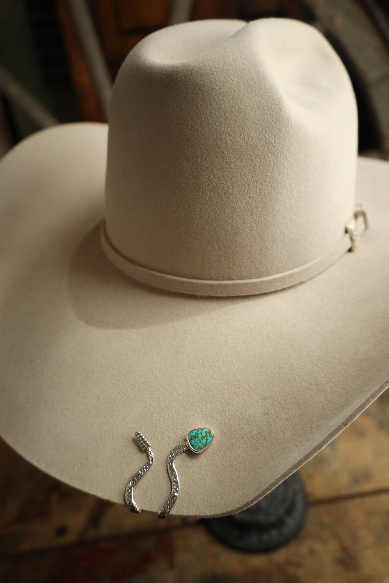 Silver earrings with a turquoise stone on a beige surface