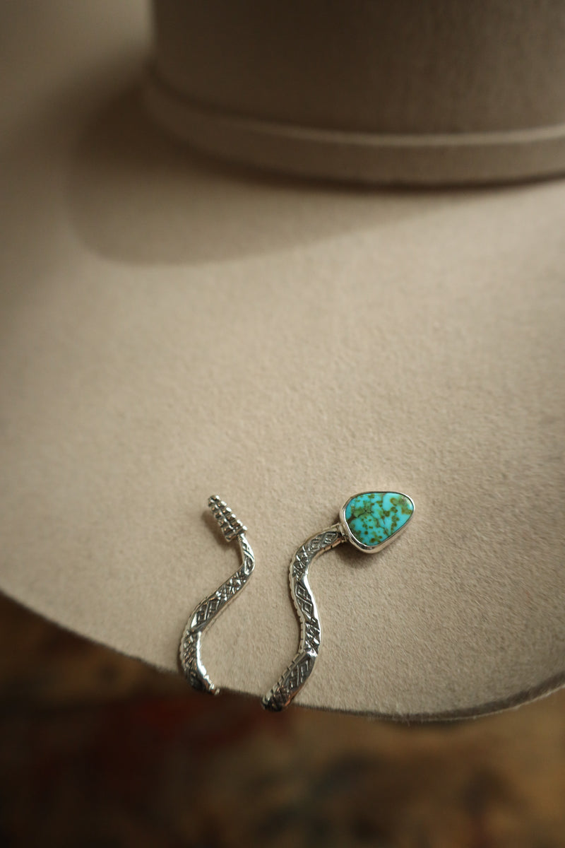 Silver earrings with a turquoise stone on a beige surface