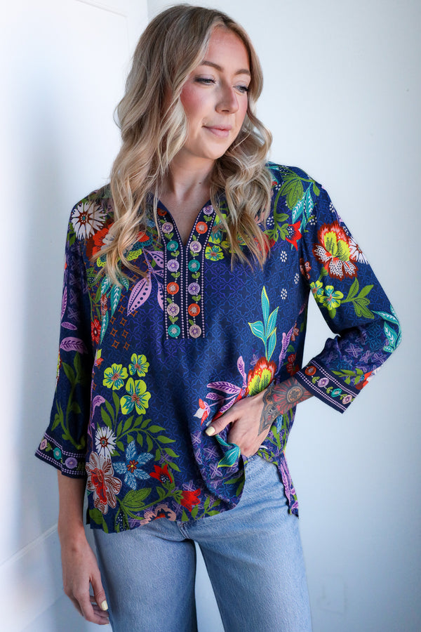 Woman wearing a colorful floral blouse against a white background