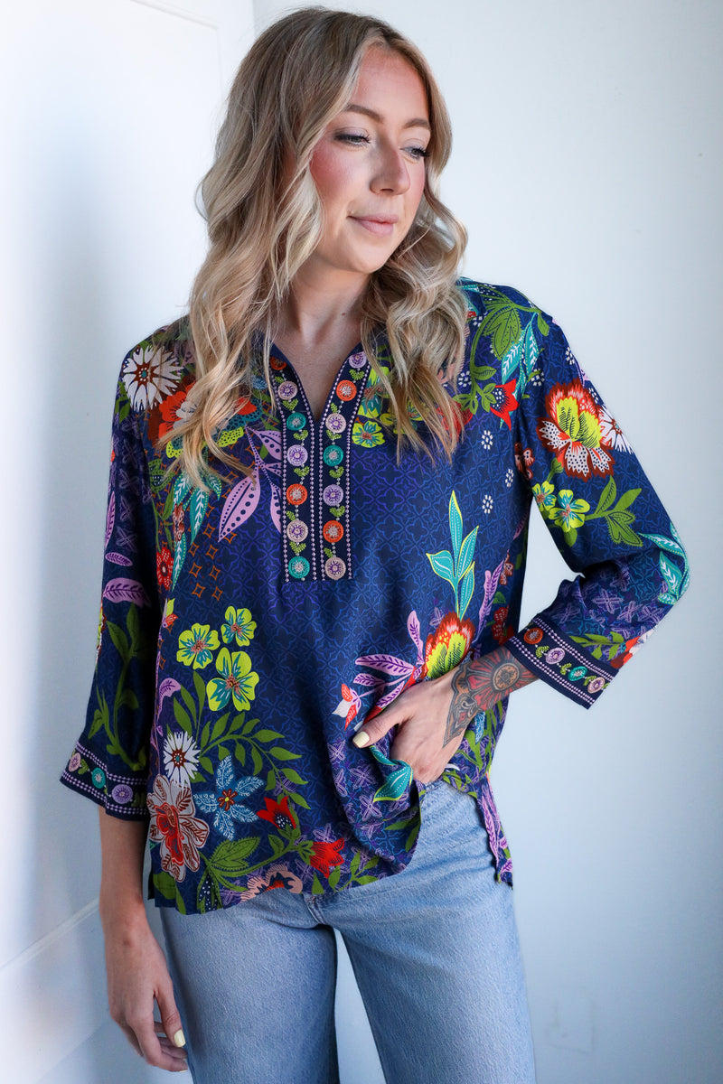 Woman wearing a colorful floral blouse against a white background