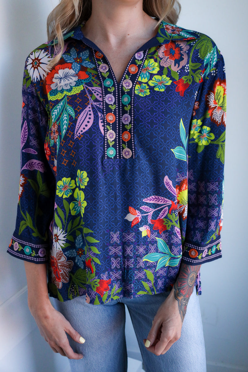 Navy blue blouse with colorful floral embroidery worn by a person against a white background