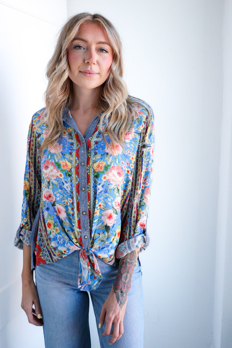 Woman wearing a colorful floral blouse against a white background