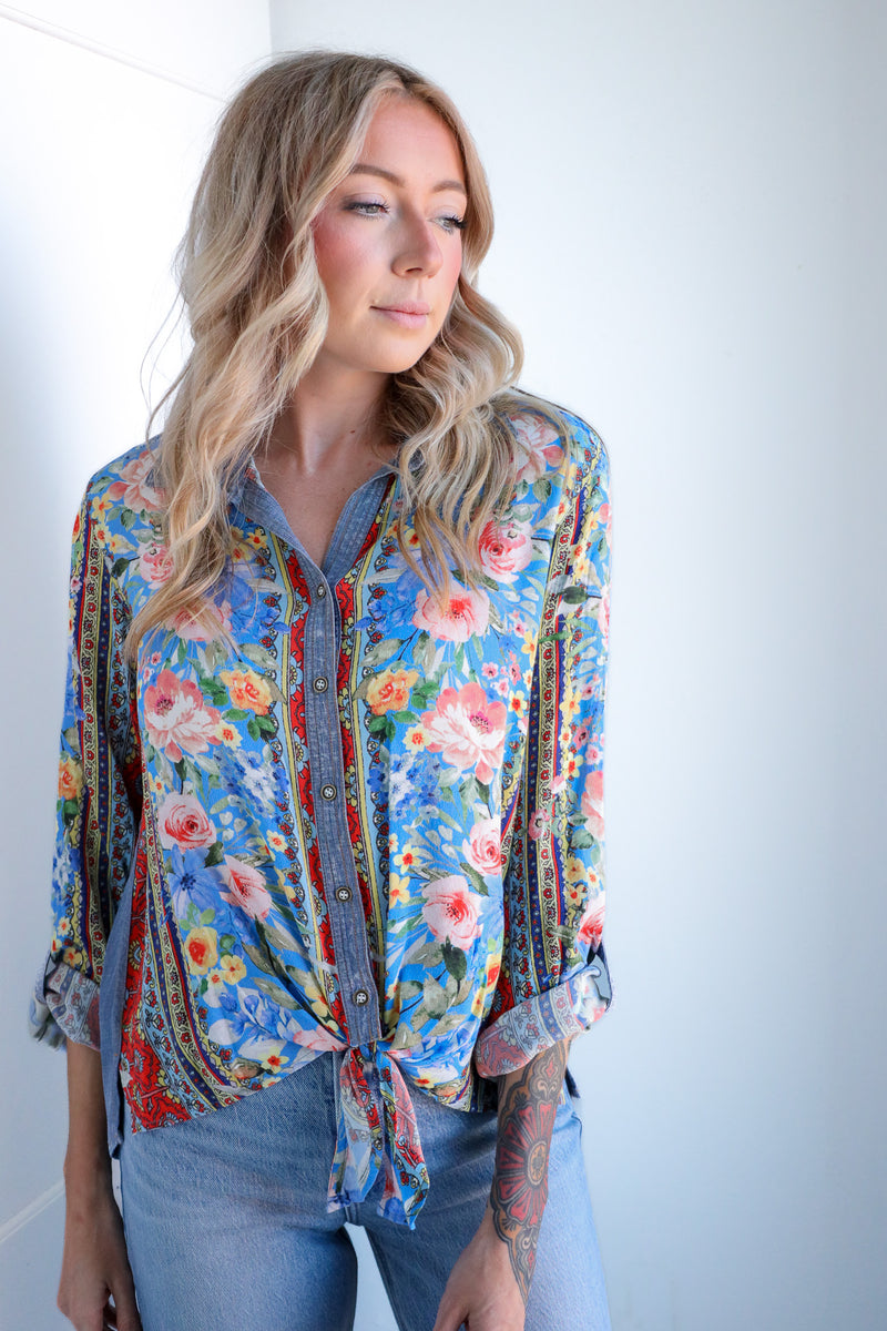 Woman wearing a colorful floral blouse against a plain background