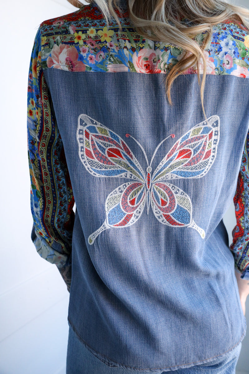 Denim shirt with a colorful butterfly design on a plain background