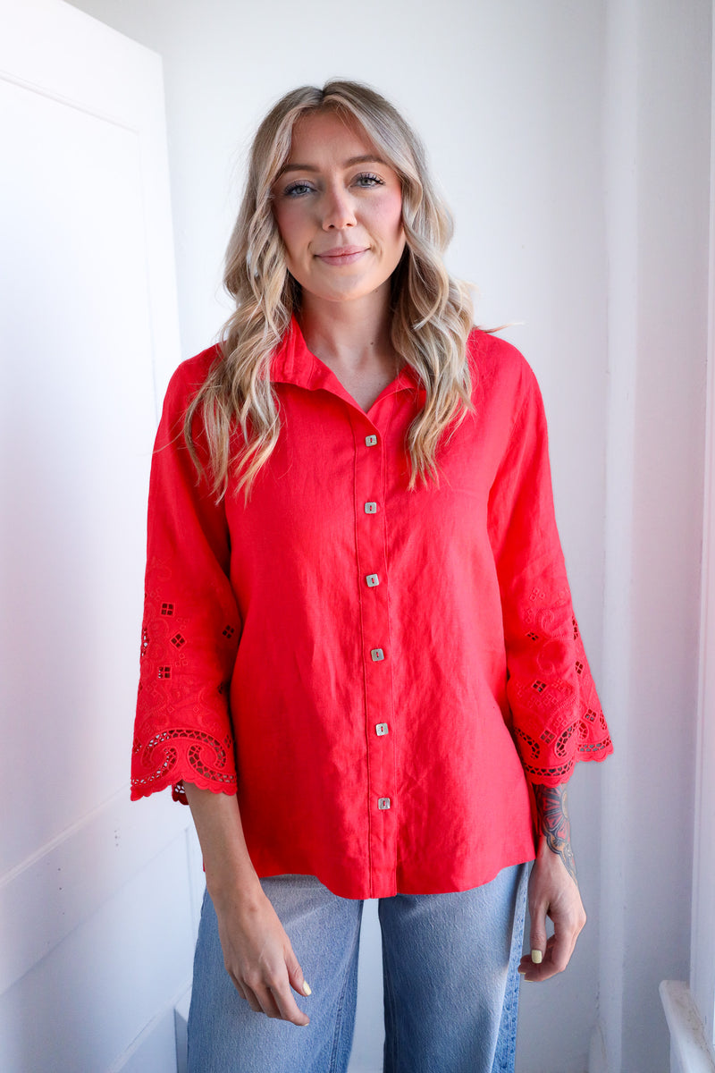 Woman wearing a red blouse with lace details against a white background