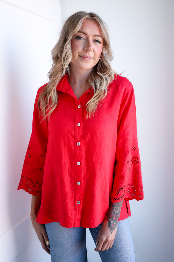 Woman wearing a red blouse with lace details against a white background