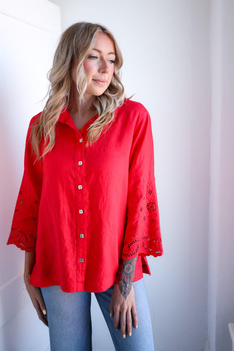 Woman wearing a red blouse with bell sleeves against a white background