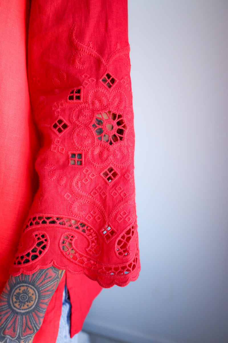 Red lace garment with intricate patterns on a light gray background