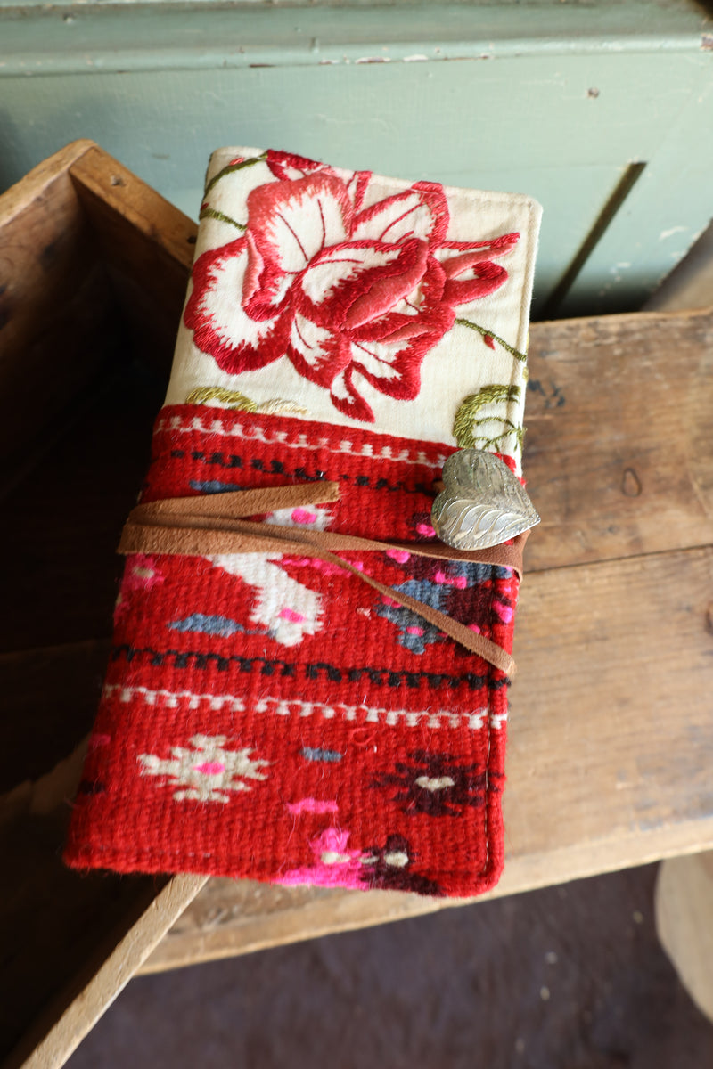 This unique clutch features a captivating combination of half red wool Aztec design and half floral embroidered flowers. Complete with a silver heart concho and leather tie purse