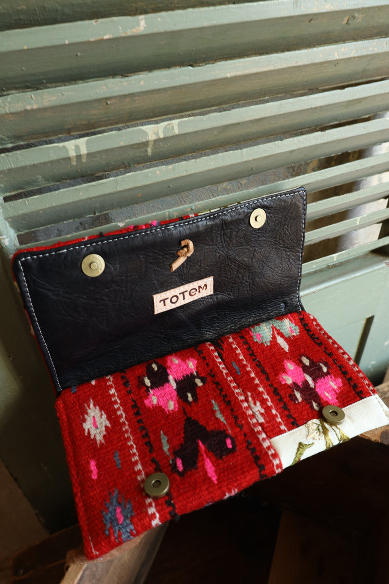 This unique clutch features a captivating combination of half red wool Aztec design and half floral embroidered flowers. Complete with a silver heart concho and leather tie purse