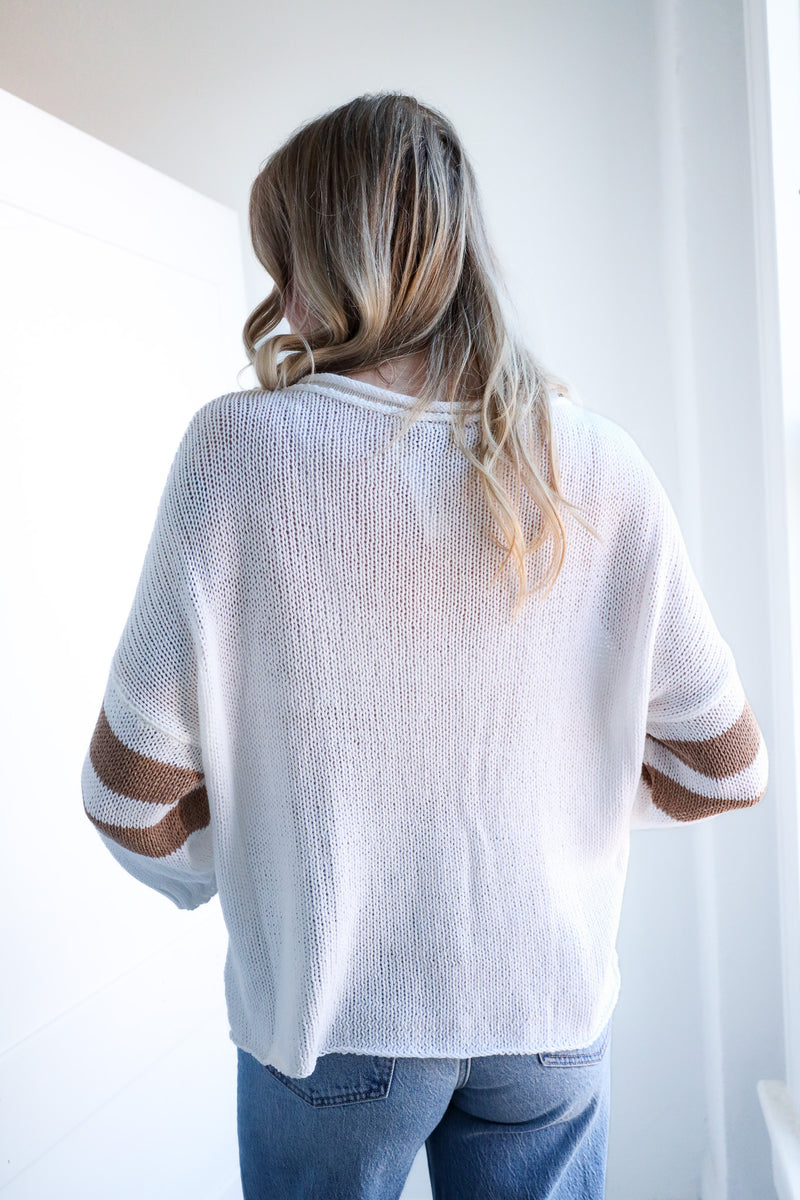 Person wearing a white mesh top with sheer sleeves against a white background
