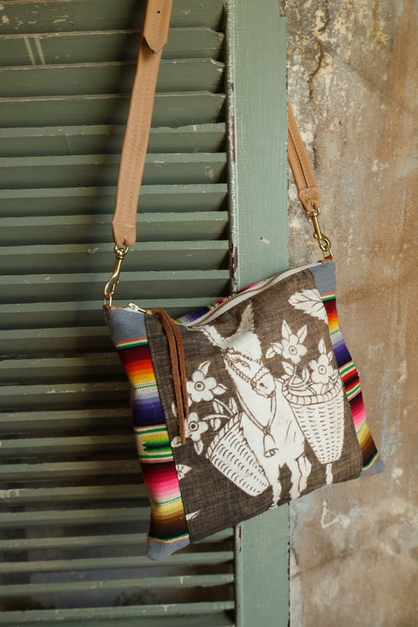 Crossbody purse with charming burro design with baskets of flowers on the front and vibrant serape sides and back.