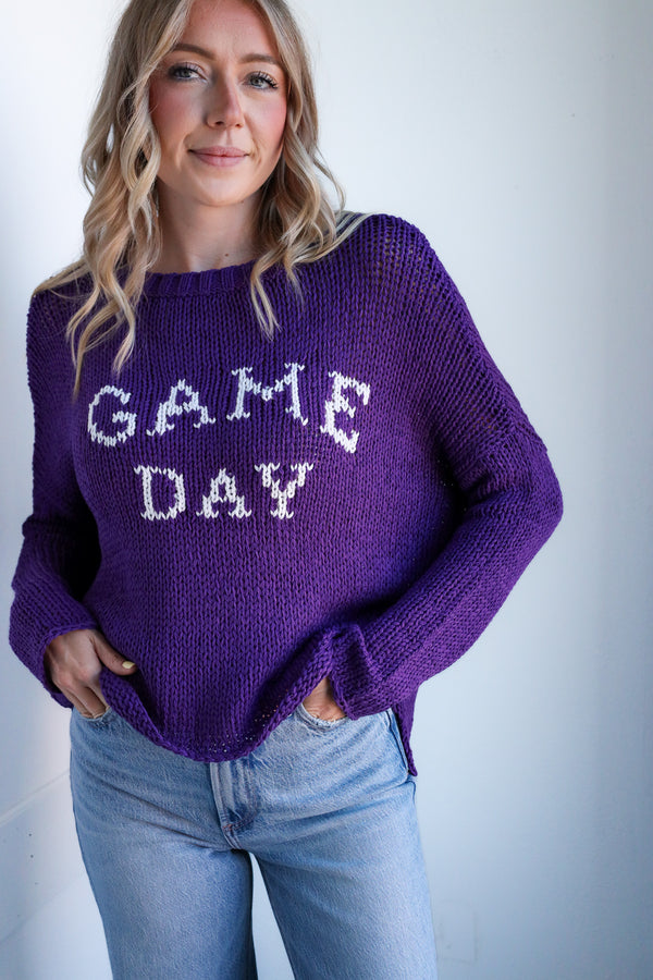 Woman wearing a purple 'GAME DAY' sweater against a plain background