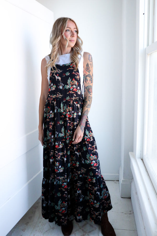 Woman wearing a floral dress standing in a bright room with white walls and a window.