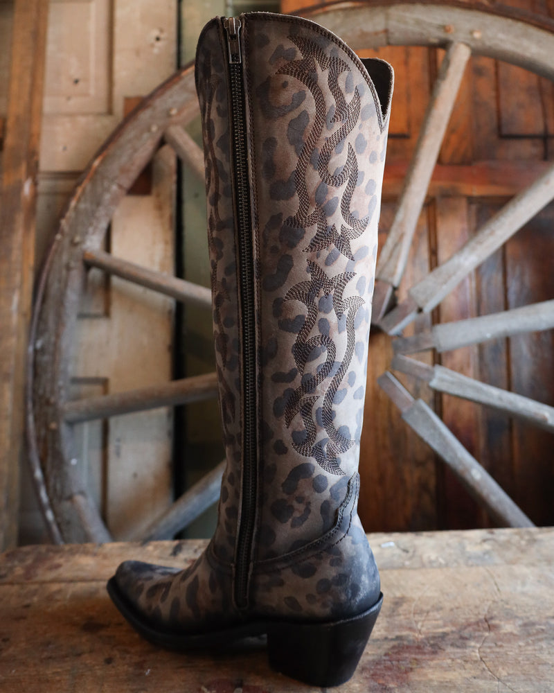 Leopard print boot with a zipper on a wooden surface with a rustic wheel background