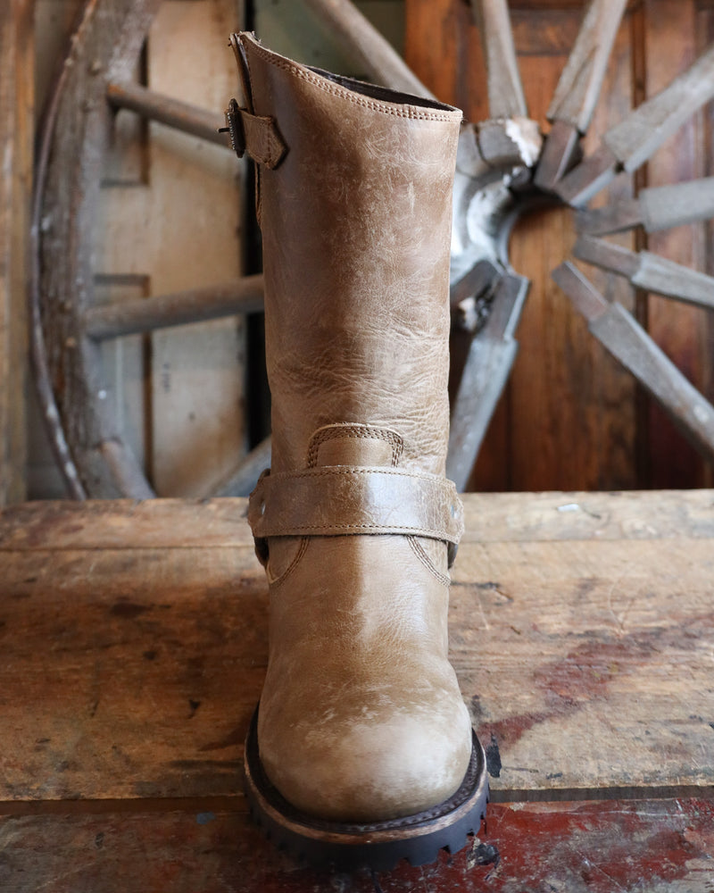 Brown leather boot on a wooden surface with a rustic background