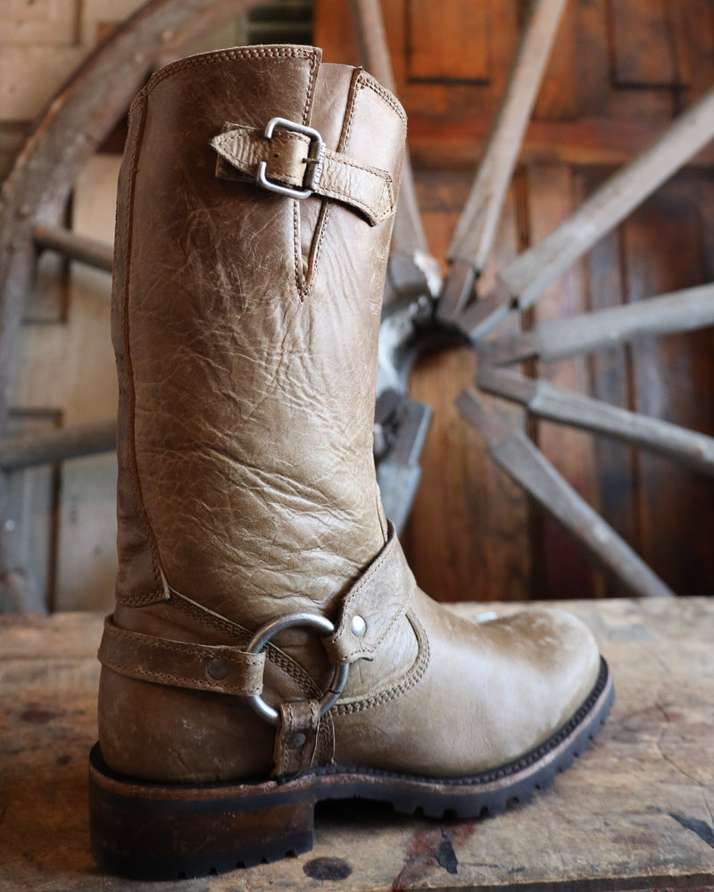 Brown leather boot with buckles on a wooden surface with a rustic background