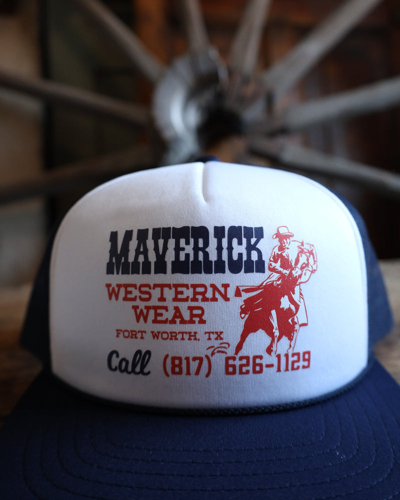 Blue and white cap with 'Maverick Western Wear' branding and contact information, against a blurred background.