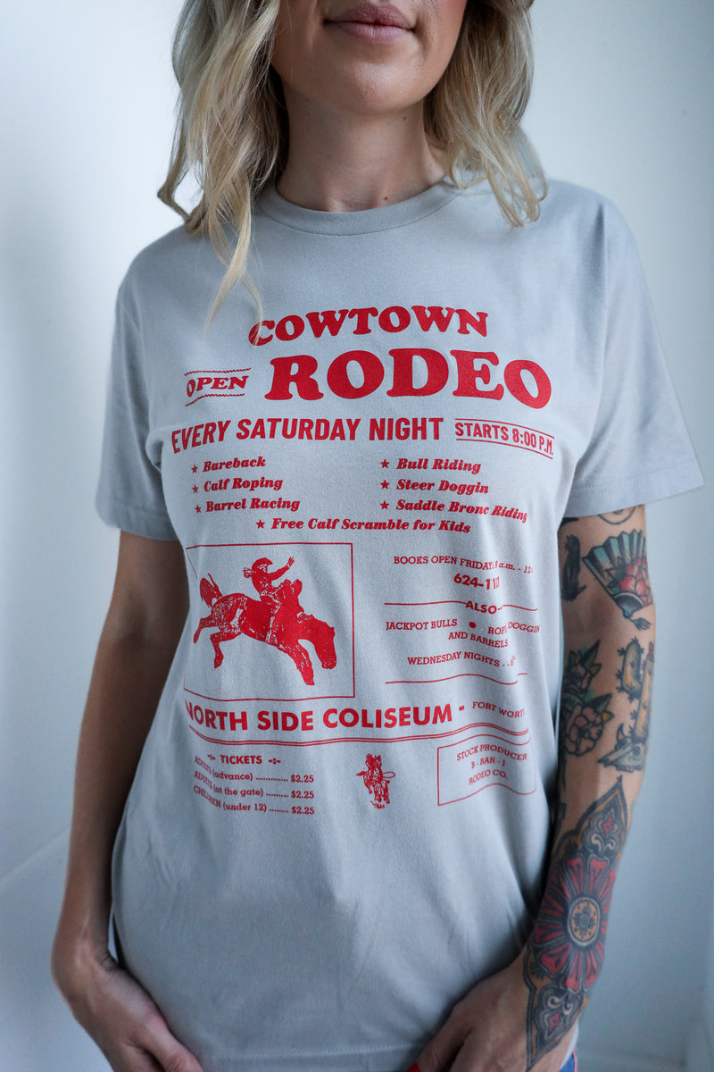 Person wearing a gray t-shirt with red 'Cowtown Rodeo' text and graphics.
