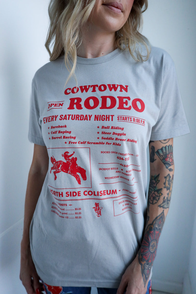 Person wearing a white t-shirt with red 'Cowtown Rodeo' text and graphics.