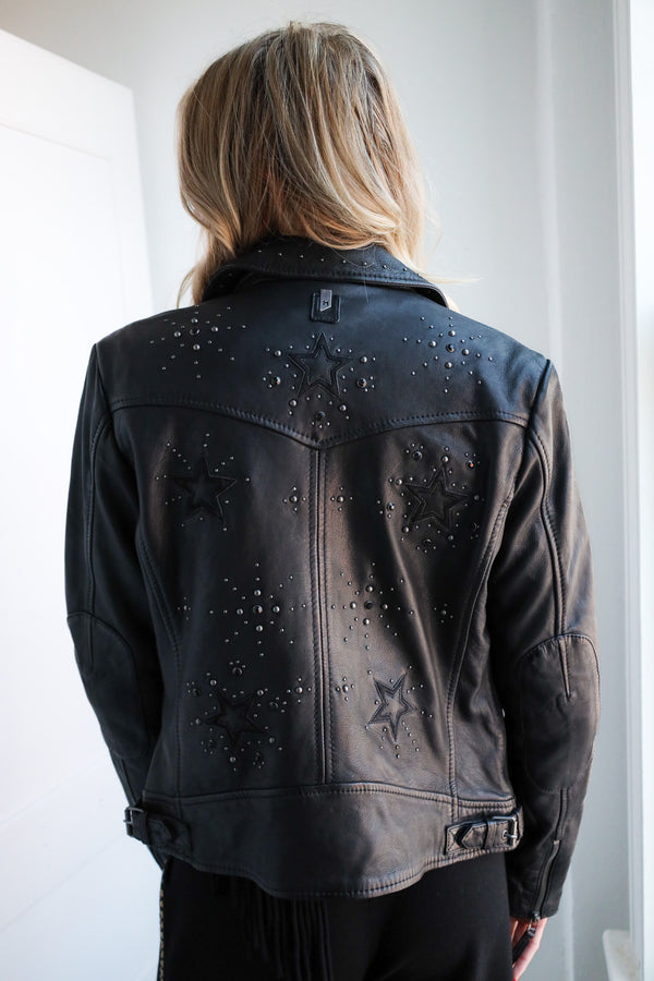 Person wearing a black leather jacket with star designs and embellishments.