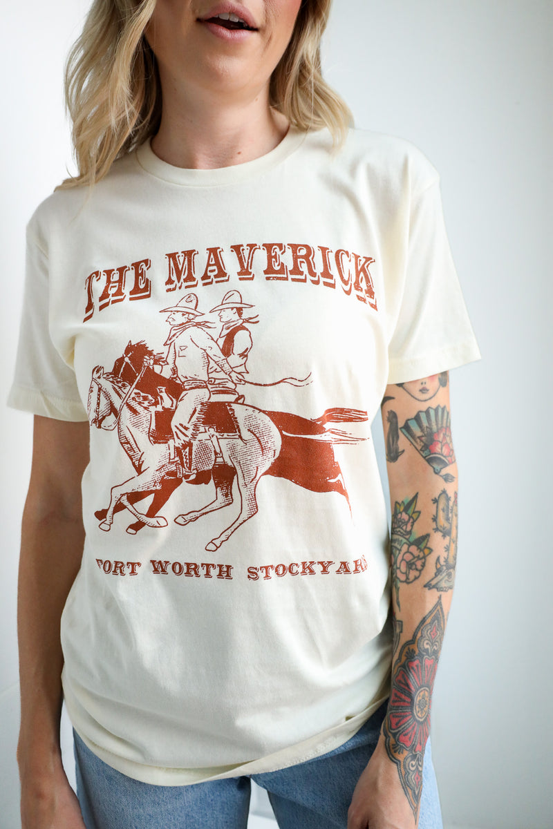 Person wearing a white t-shirt with 'The Mavericks Fort Worth Stockyards' graphic design.
