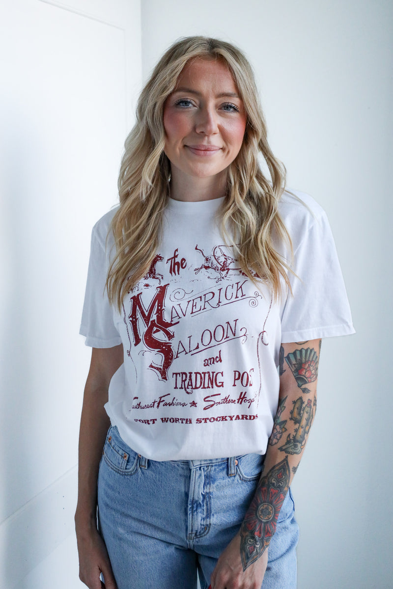 Woman wearing a white t-shirt with red graphics and text, standing against a plain background