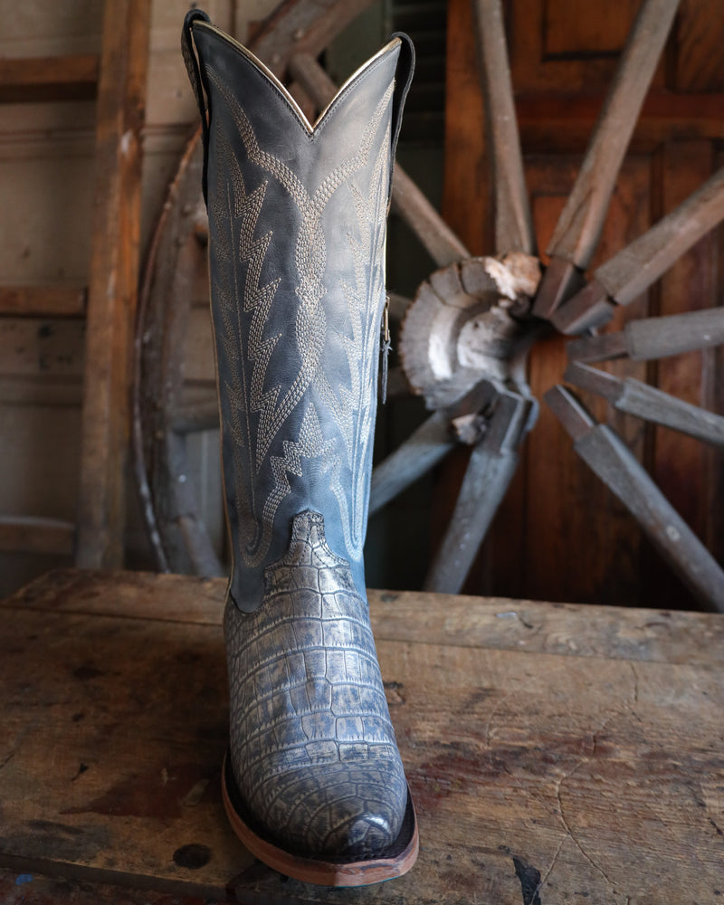 Blue cowboy boot with intricate patterns on a wooden surface with a rustic background