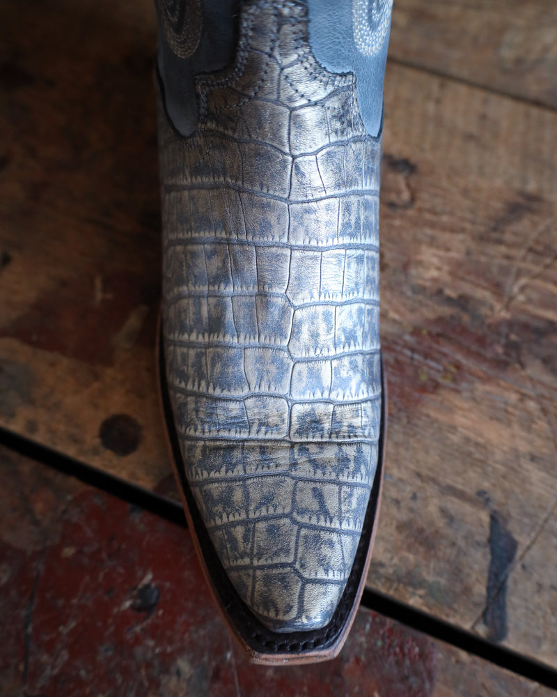 Close-up of a shoe with a textured pattern on a wooden floor.