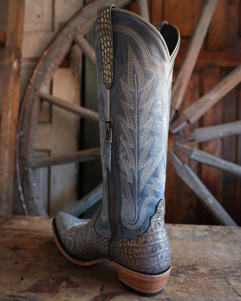 Cowboy boot with intricate design on a wooden surface with a rustic background