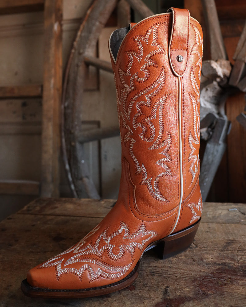 Brown cowboy boot with white embroidery on a wooden surface