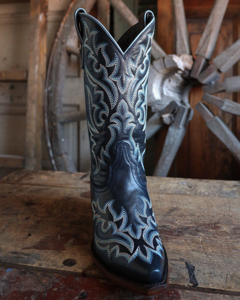 Navy blue cowboy boot with white embroidery on a wooden surface with a rustic background