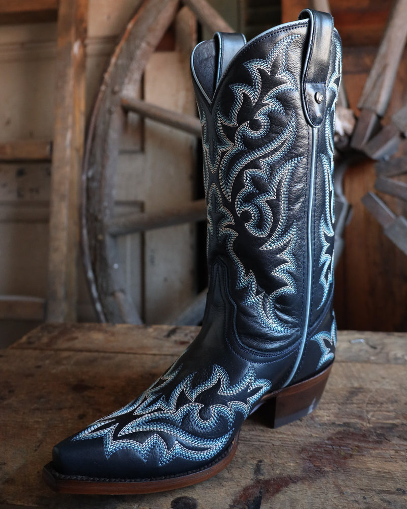 Blue embroidered cowboy boot on a wooden surface with a rustic background