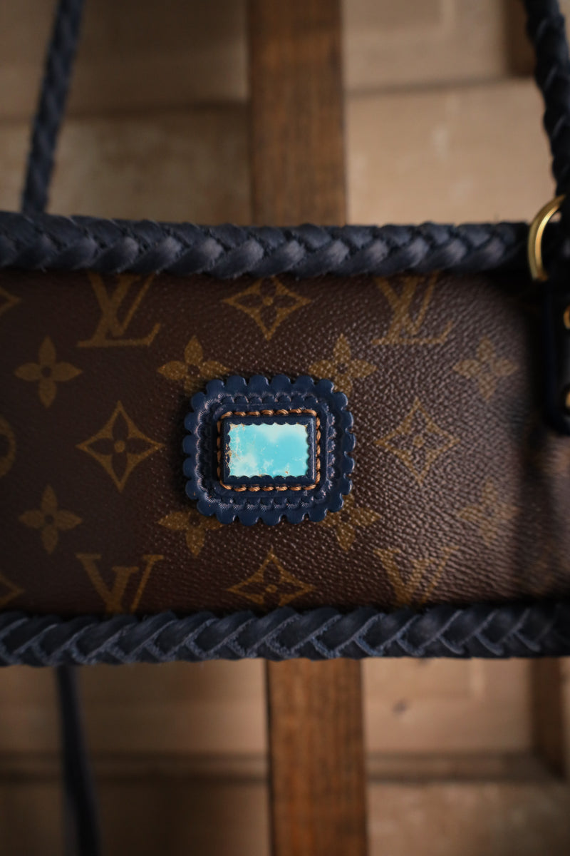 Louis Vuitton handbag with a distinctive patch on a wooden stand