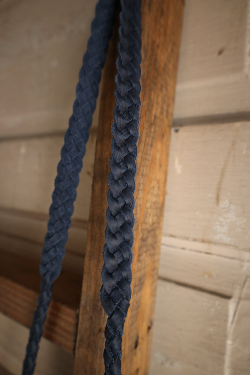 Two braided blue ropes hanging on a wooden surface with a neutral background
