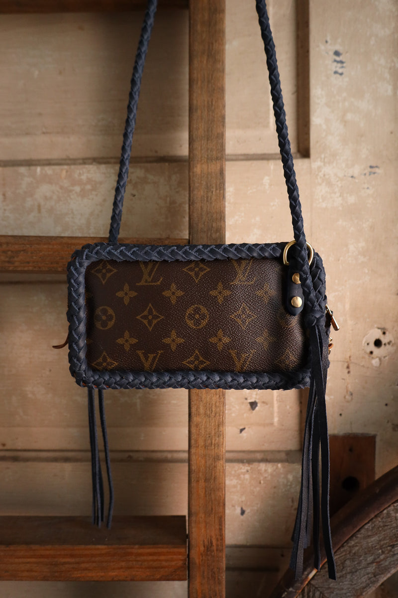 Brown handbag with braided handle and visible brand logo on a wooden surface