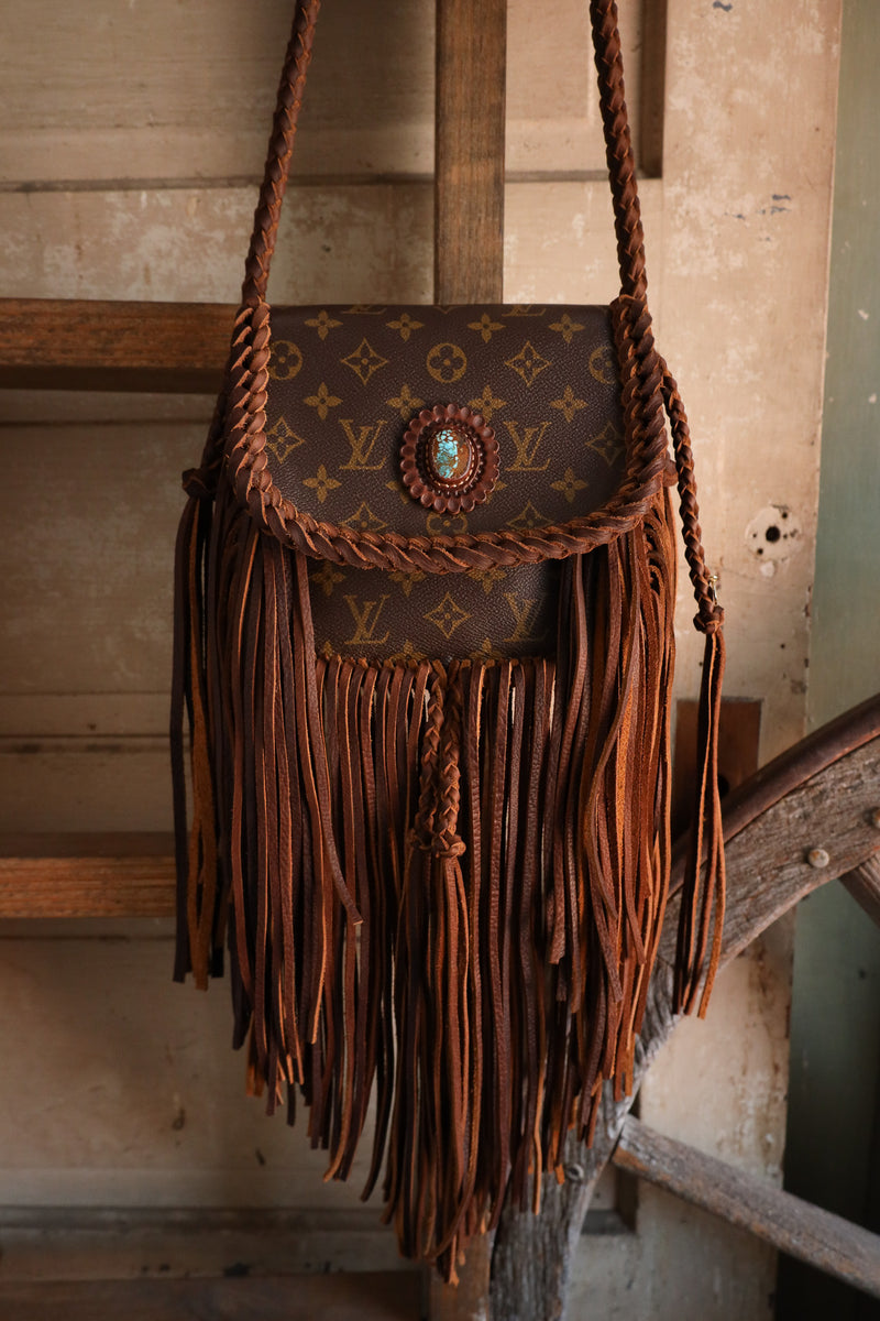 Designer handbag with fringe and decorative element on a wooden surface