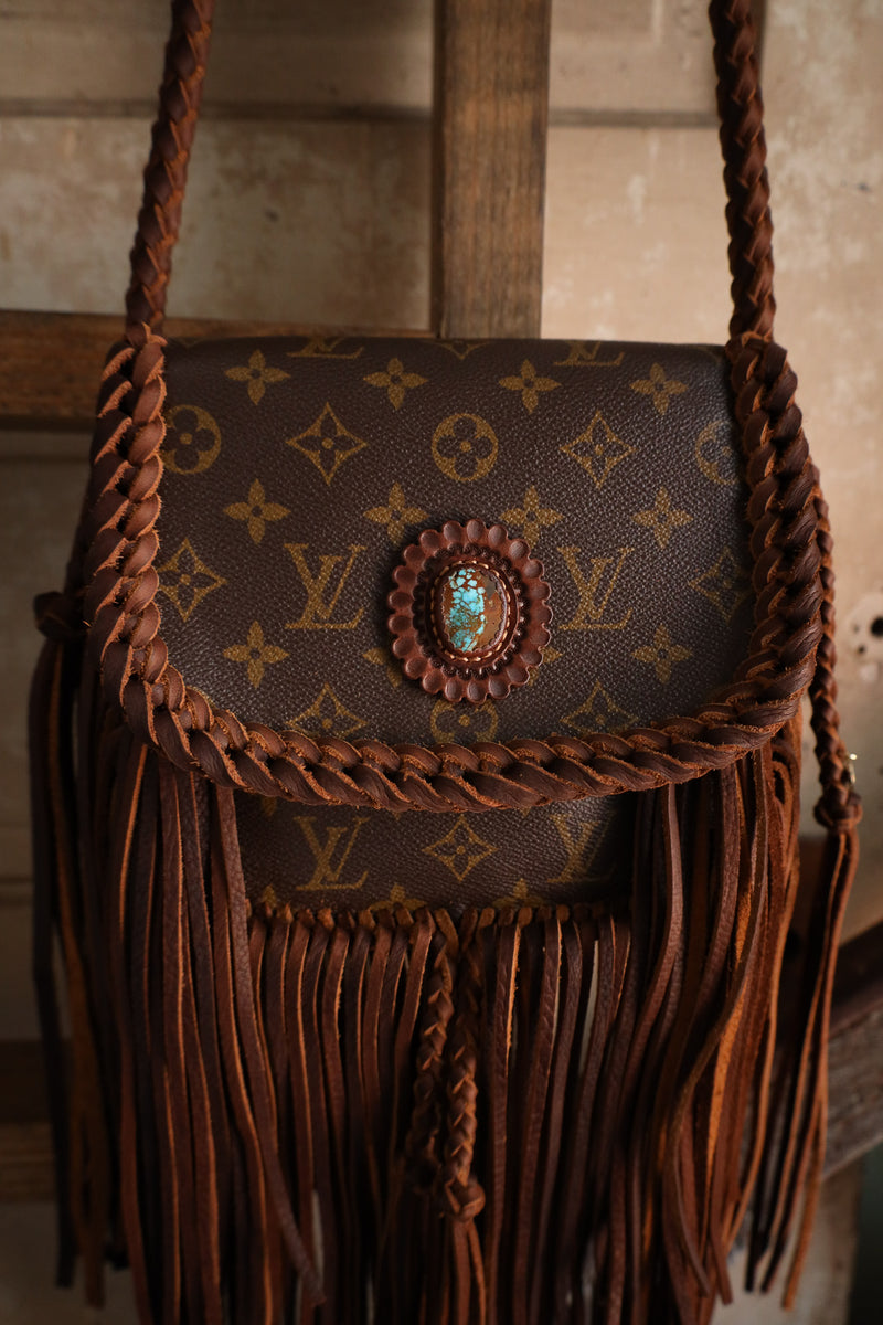Brown handbag with fringes and decorative element on a wooden surface