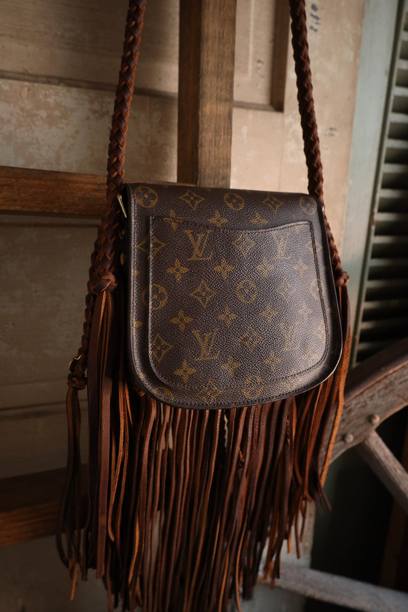 Brown leather handbag with fringes on a wooden background