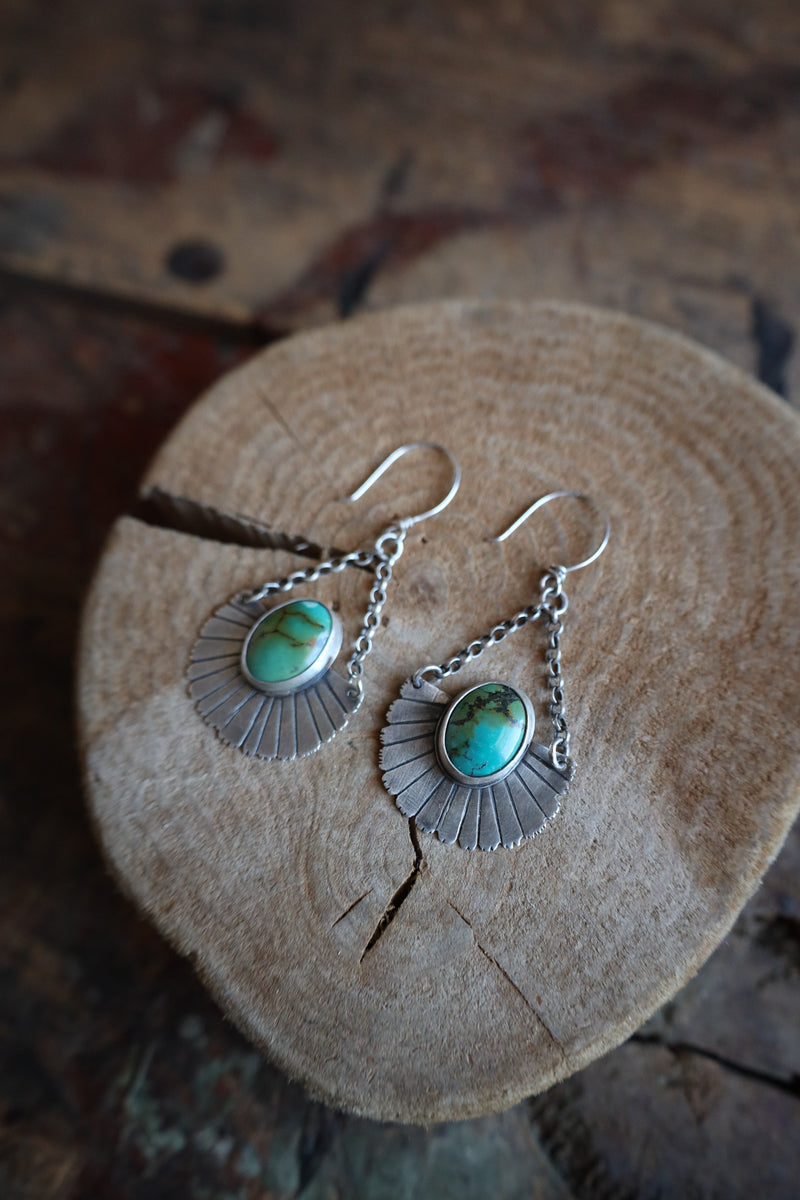 Silver earrings with turquoise stones on a wooden surface