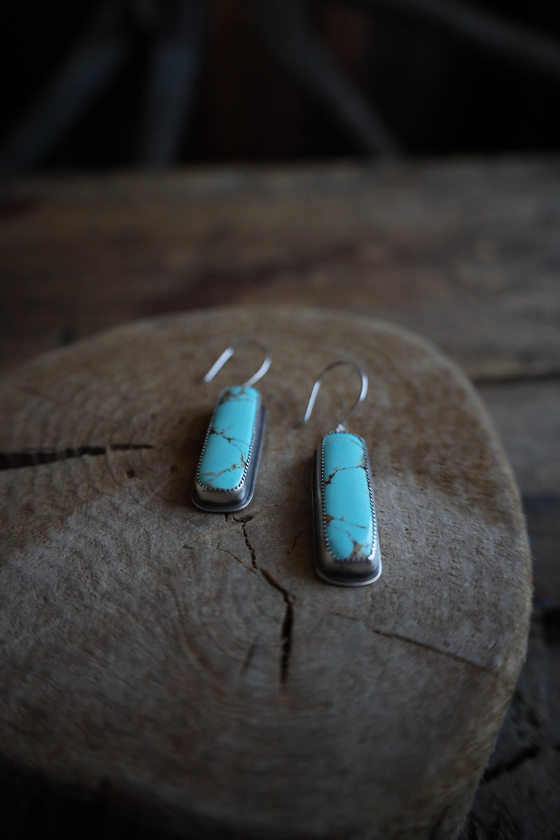 Turquoise earrings on a wooden surface