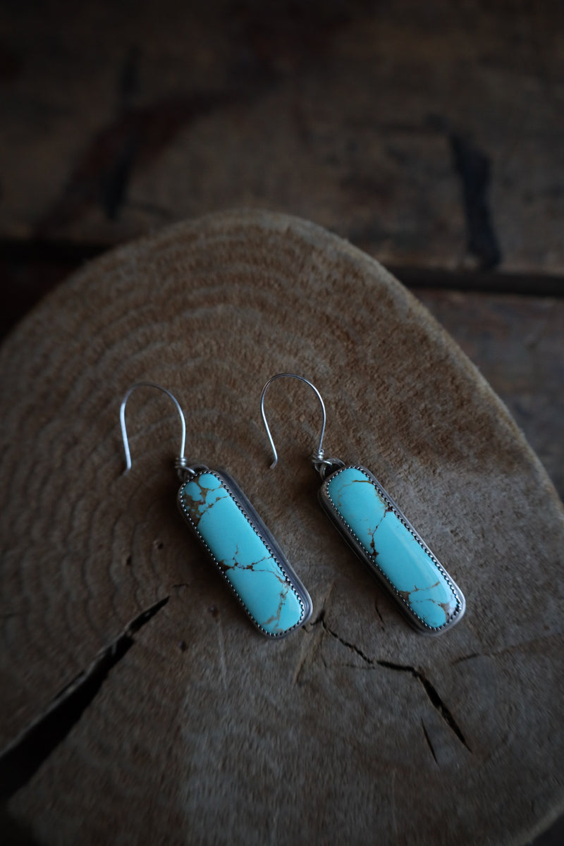 Turquoise earrings on a wooden surface