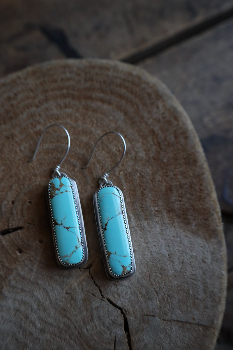 Turquoise earrings on a wooden surface