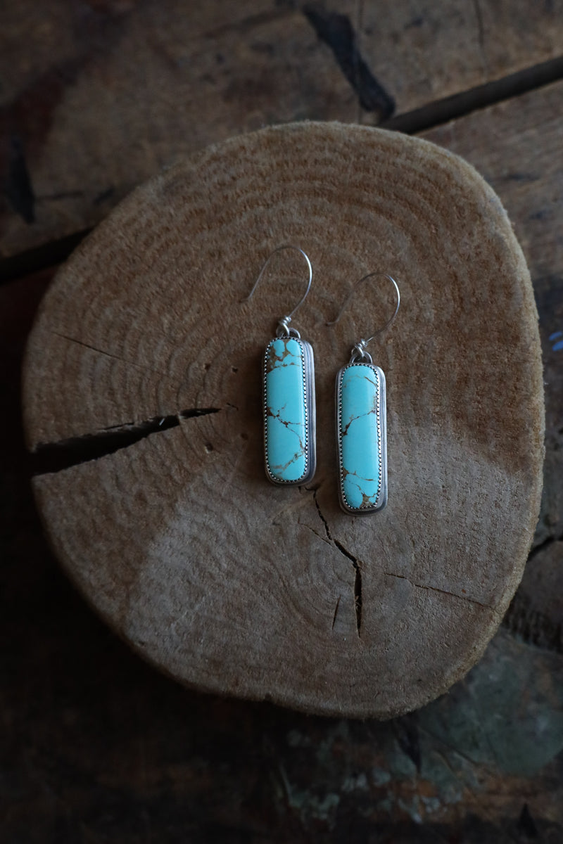 Turquoise earrings on a wooden surface