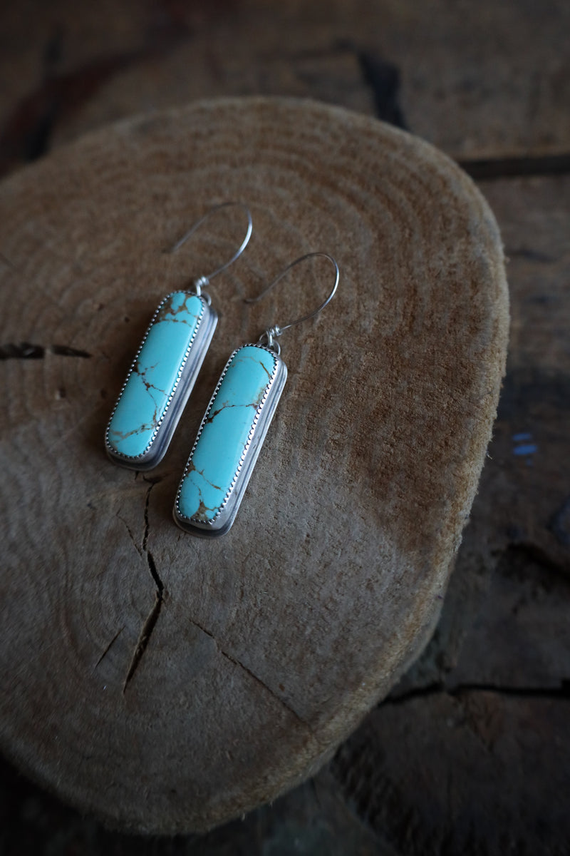 Turquoise earrings on a wooden surface