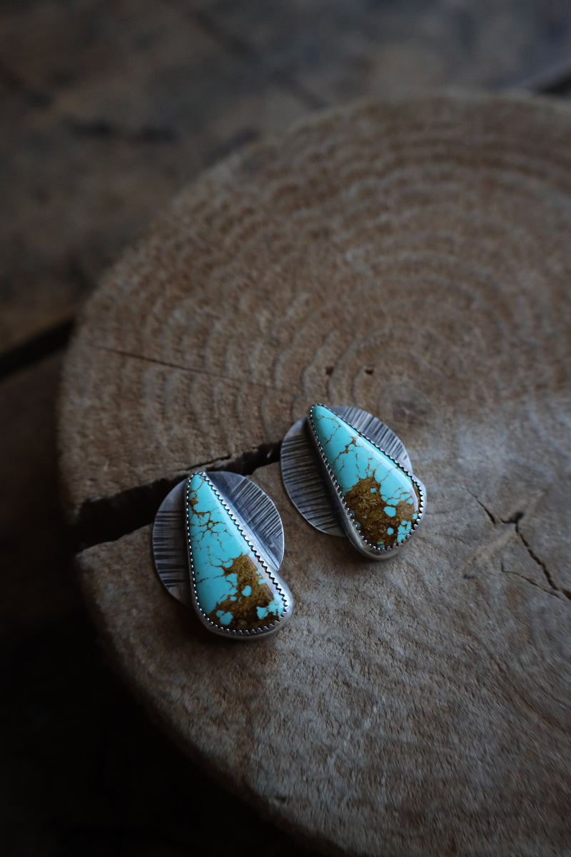 Turquoise stone earrings on a wooden surface