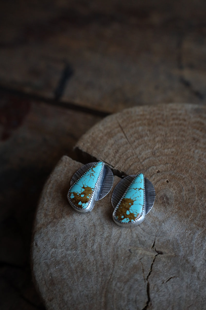 Turquoise and silver earrings on a wooden surface