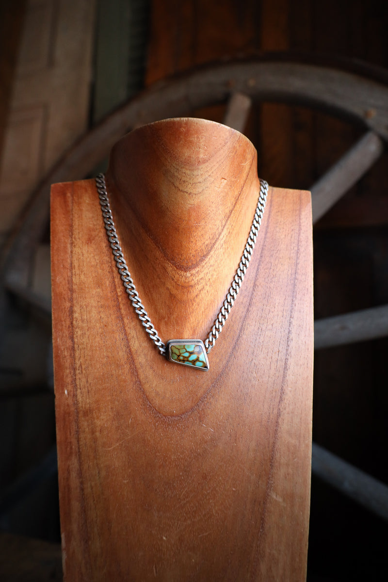 Necklace with a turquoise pendant on a wooden stand, rustic background