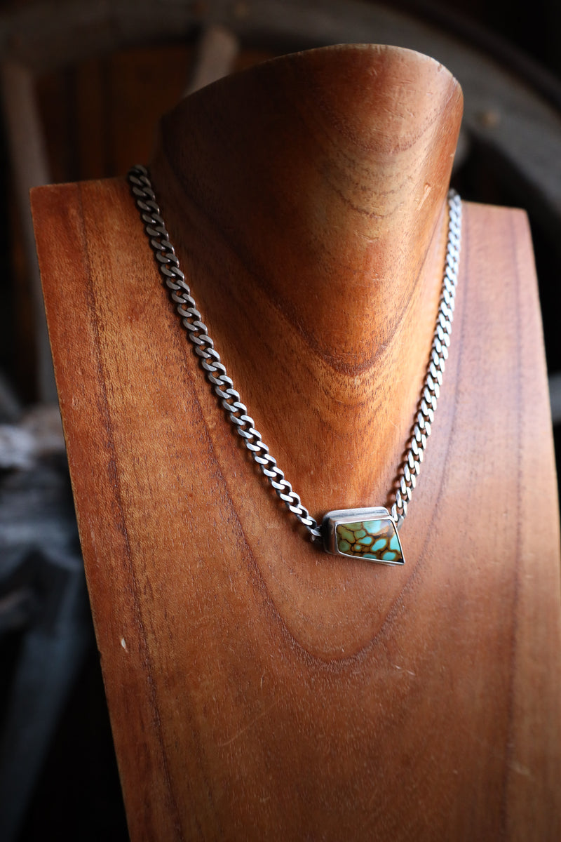 Necklace with a turquoise pendant on a wooden stand