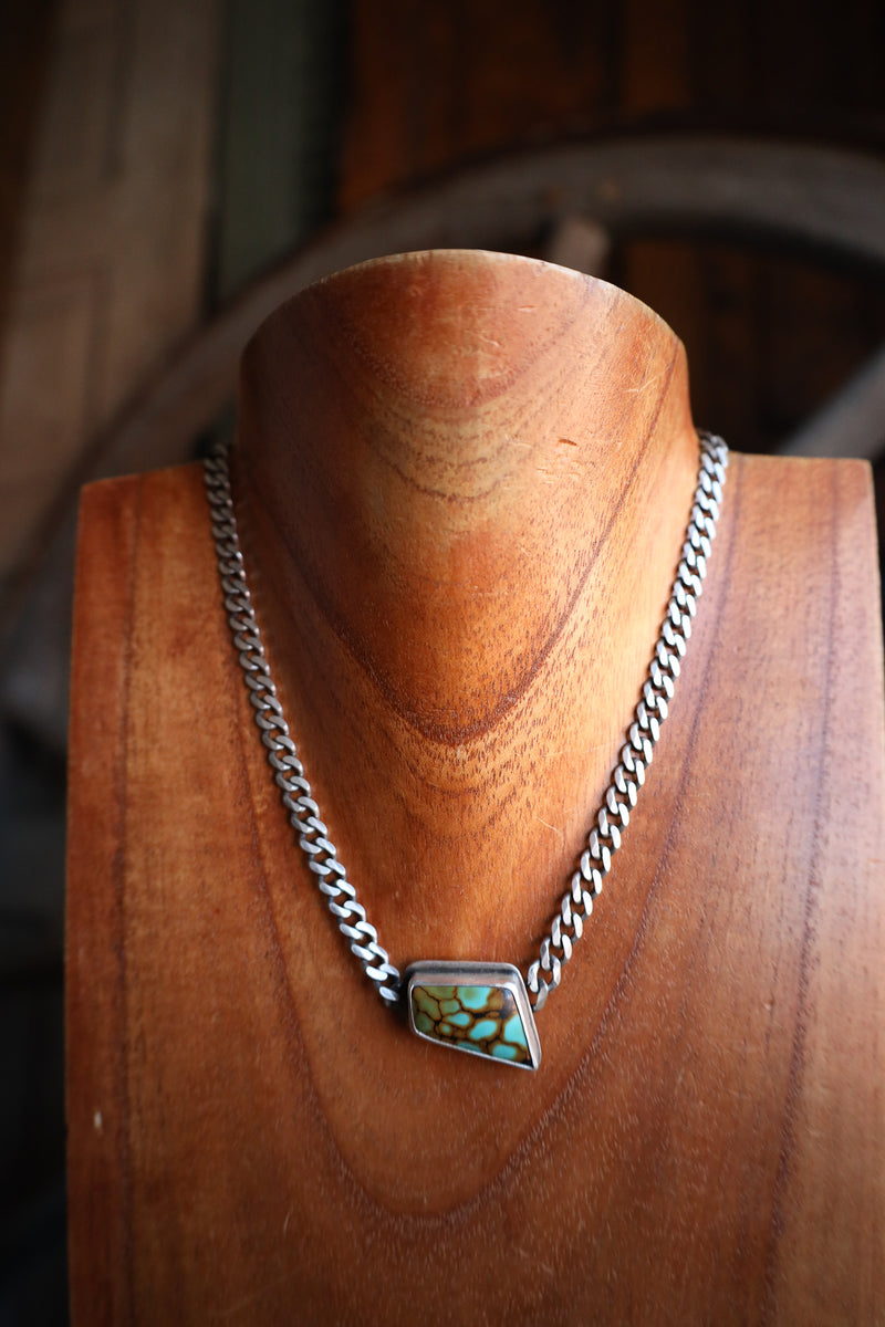 Necklace with a turquoise pendant on a wooden mannequin